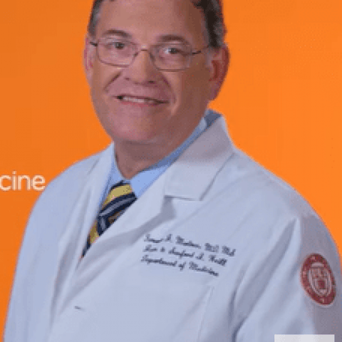 person in white lab coat in front of an orange background